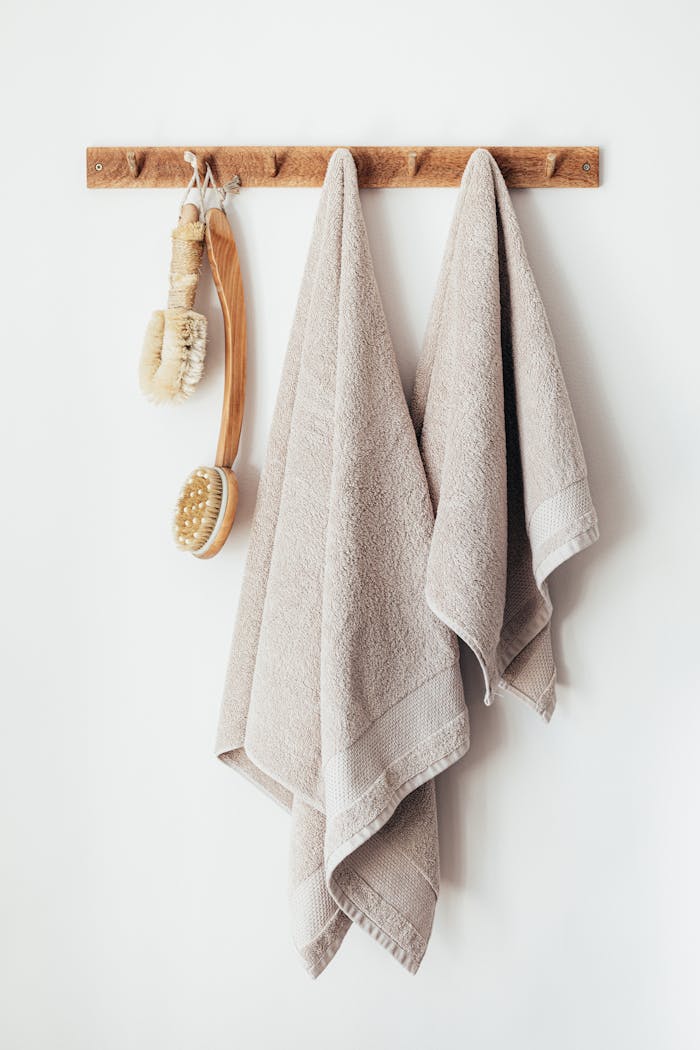 Elegant bathroom decor featuring soft towels and eco-friendly brushes on a wooden hanger.